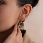 Close-up of a person wearing the Bold Duo Knot Earrings, touching their earlobe with their hand.