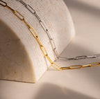 The Bold Paperclip Chain Necklace drapes elegantly over a curved marble surface in soft lighting, making a striking statement for a bold necklace look.