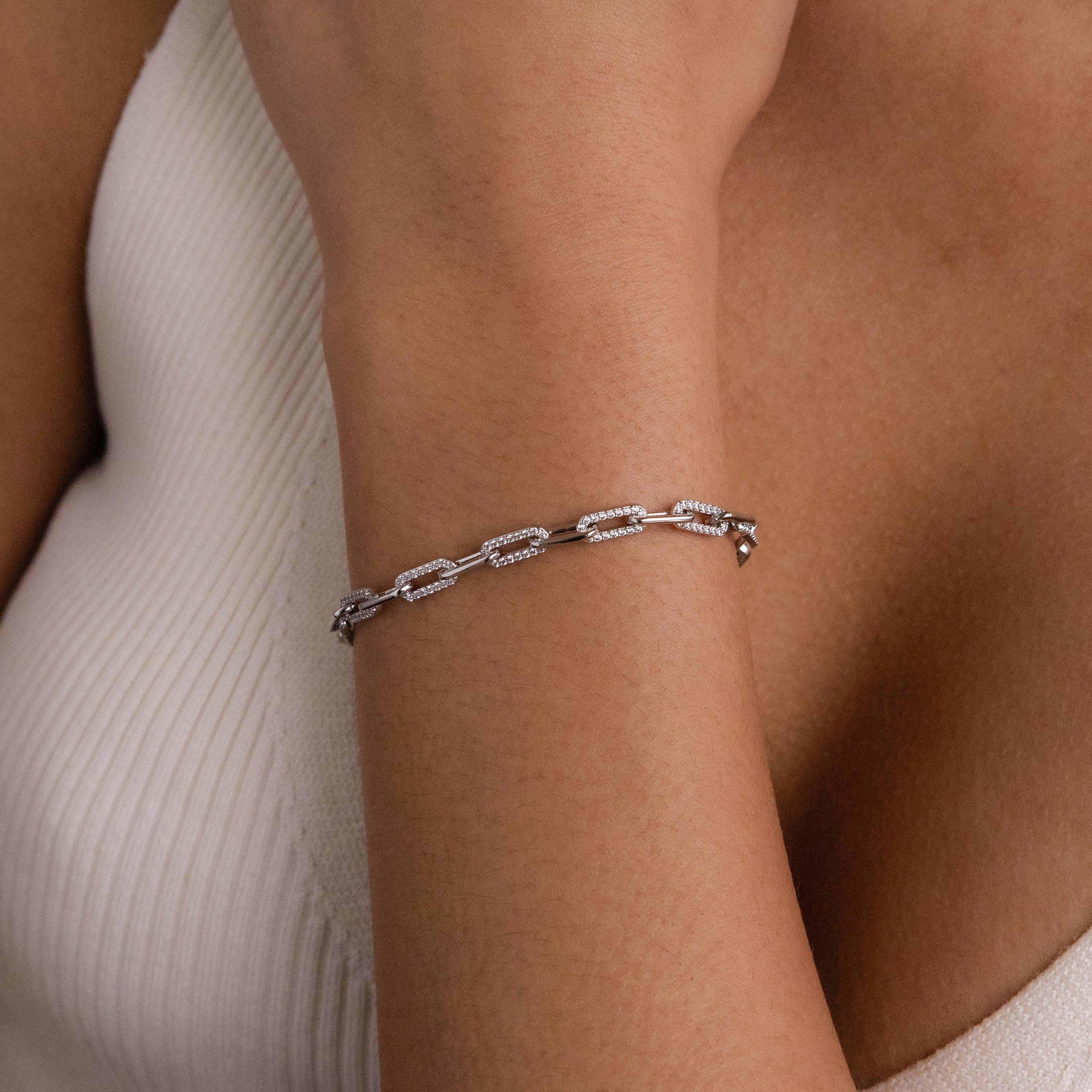 The Pave Paperclip Chain Bracelet adds sparkle to a wrist, styled over a sleeveless white ribbed top.