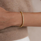 A woman wears the S-Link Diamond Tennis Bracelet, its shimmering stones elegantly paired with a beige sweater.