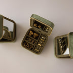 The Velvet Mirror Jewelry Box in green velvet opens to show neatly organized gold rings and earrings beside built-in mirrors—perfect for stylish, secure travel storage of your favorite accessories.