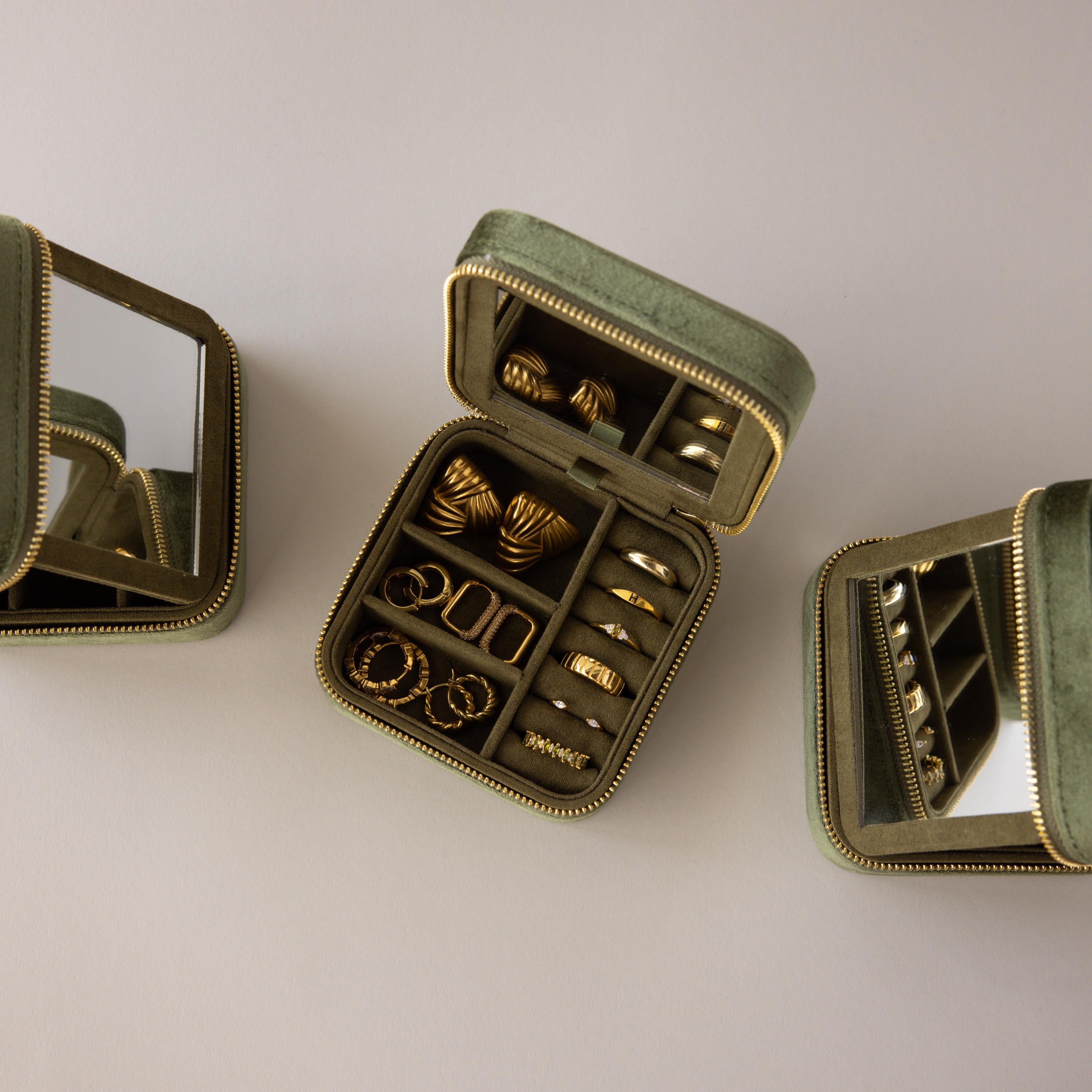 The Velvet Mirror Jewelry Box in green velvet opens to show neatly organized gold rings and earrings beside built-in mirrors—perfect for stylish, secure travel storage of your favorite accessories.