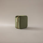 The Velvet Mirror Jewelry Box in olive green features a square velvet design with a gold zipper, ideal as a travel jewelry box, shown on a neutral background.