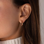 Close-up of a woman's ear wearing Baguette Birthstone Link Earrings, her brown hair framing a white sweater.