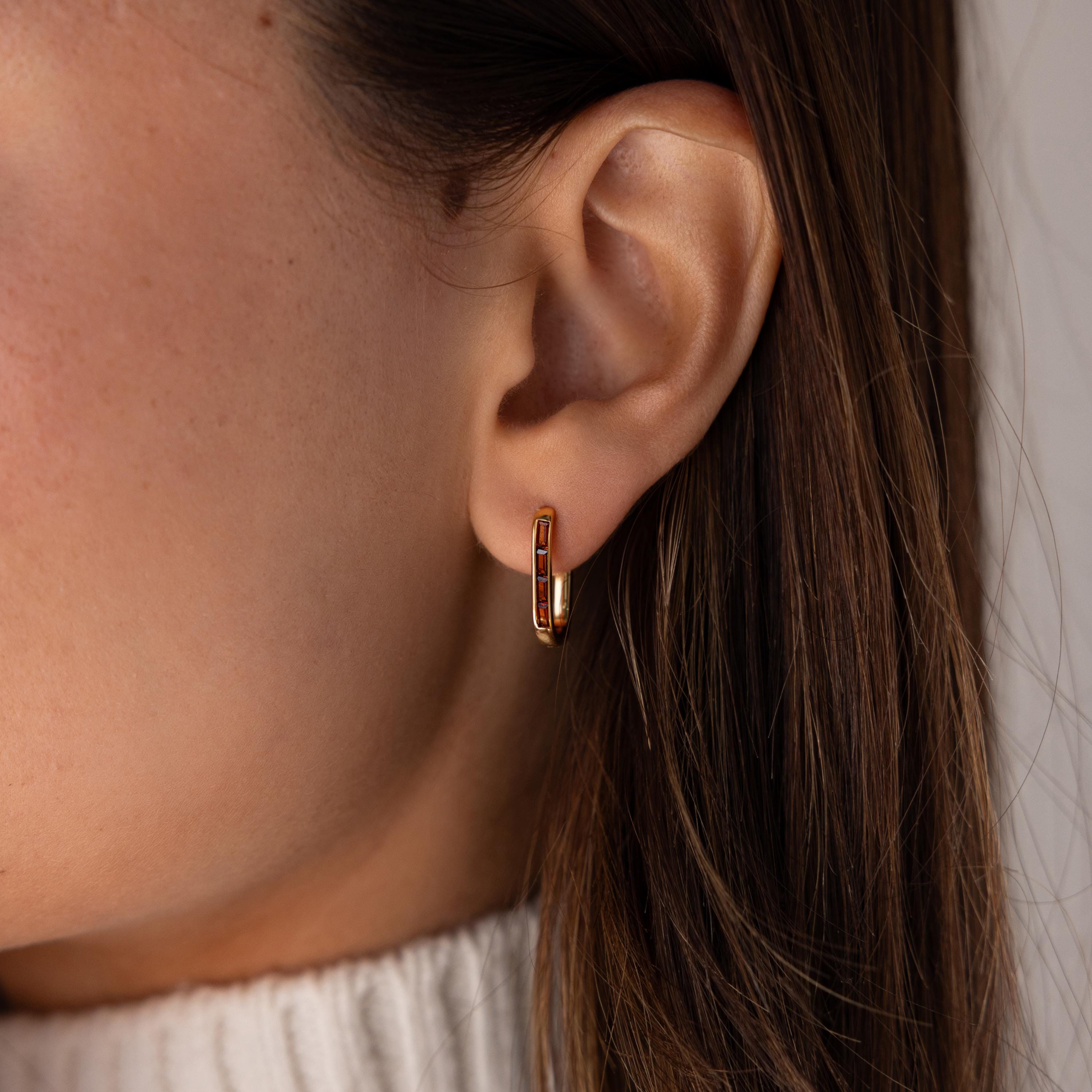 Close-up of a woman's ear wearing Baguette Birthstone Link Earrings, her brown hair framing a white sweater.