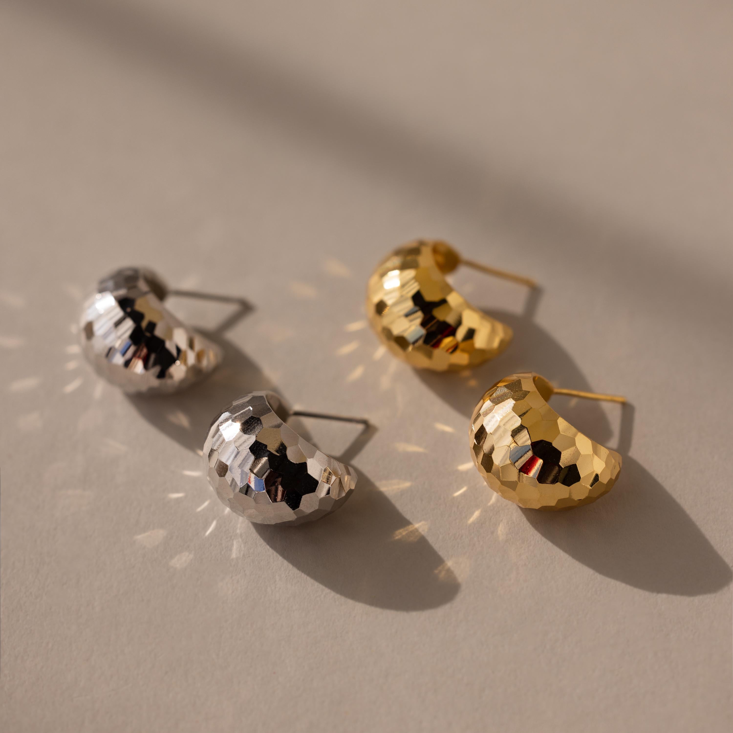 Add subtle retro glam to any look with Bold Disco Earrings—this set includes two hammered crescent-shaped stud pairs, one in silver and one in gold, for versatile style on a neutral surface.