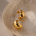 Bold Disco Earrings radiate retro glam, showcased on a light, textured dish bathed in soft, natural light.