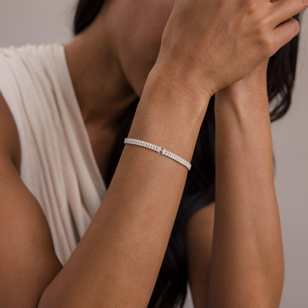 A woman in a sleeveless top showcases the Initial Duo Tennis Bracelet on her wrist, with her hands near her face.