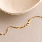 Diamond Tennis Letter Necklace spelling ASHLEY displayed on a beige surface, with a curved ceramic dish in the corner.