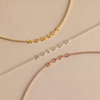Three Diamond Tennis Letter Necklaces spelling ASHLEY, AUTUMN, and HOPE in gold, silver, and rose gold are showcased on a beige background.