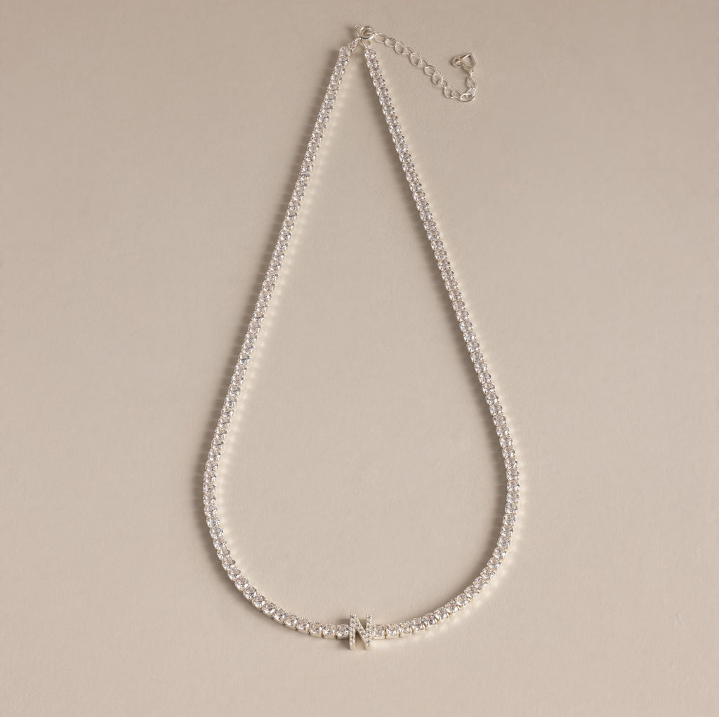 Diamond Tennis Initial Necklace featuring a sparkling initial pendant, ideal for layering with other personalized jewelry, showcased on a beige background.