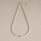 Diamond Tennis Initial Necklace featuring a sparkling initial pendant, ideal for layering with other personalized jewelry, showcased on a beige background.