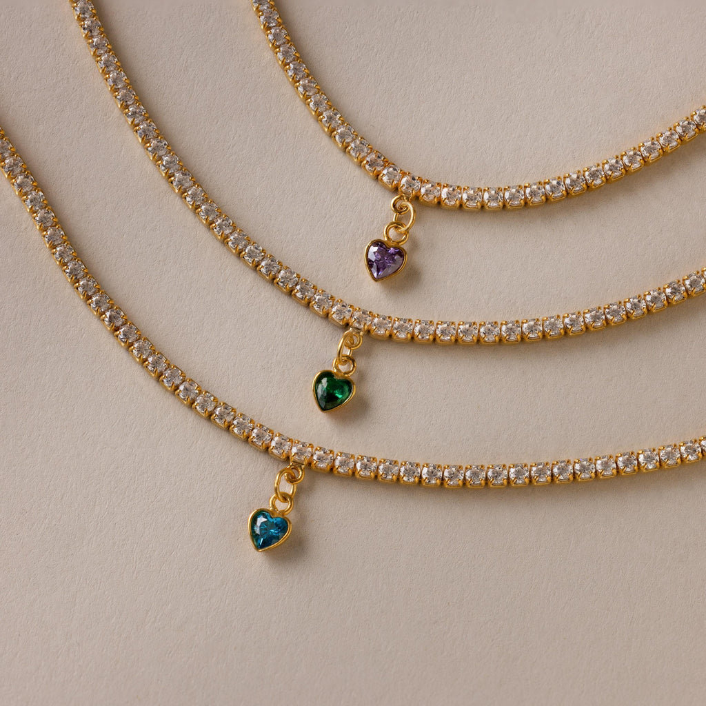Three Heart Birthstone Tennis Bracelets, each with a sparkling heart-shaped CZ gem in blue, green, and purple.