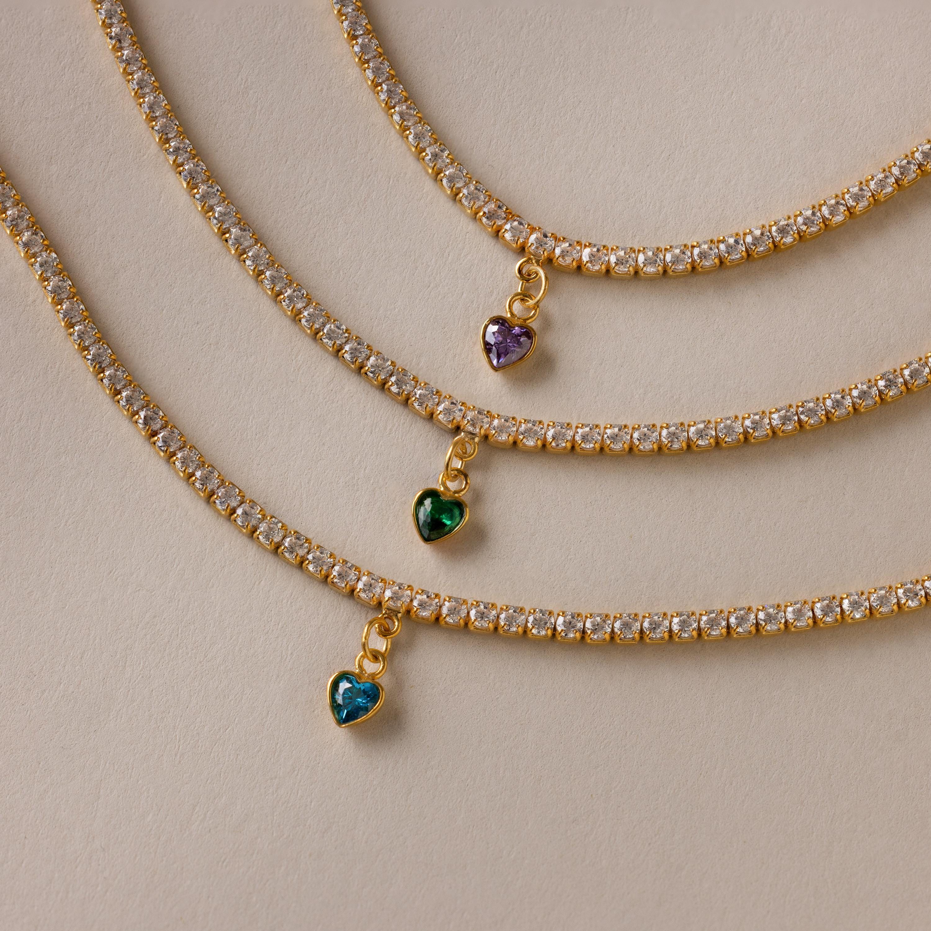 Three Heart Birthstone Tennis Bracelets, each with a sparkling heart-shaped CZ gem in blue, green, and purple.