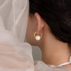 A woman wearing Bold Round Pearl Hoops with large white pearls, draped in sheer white fabric.