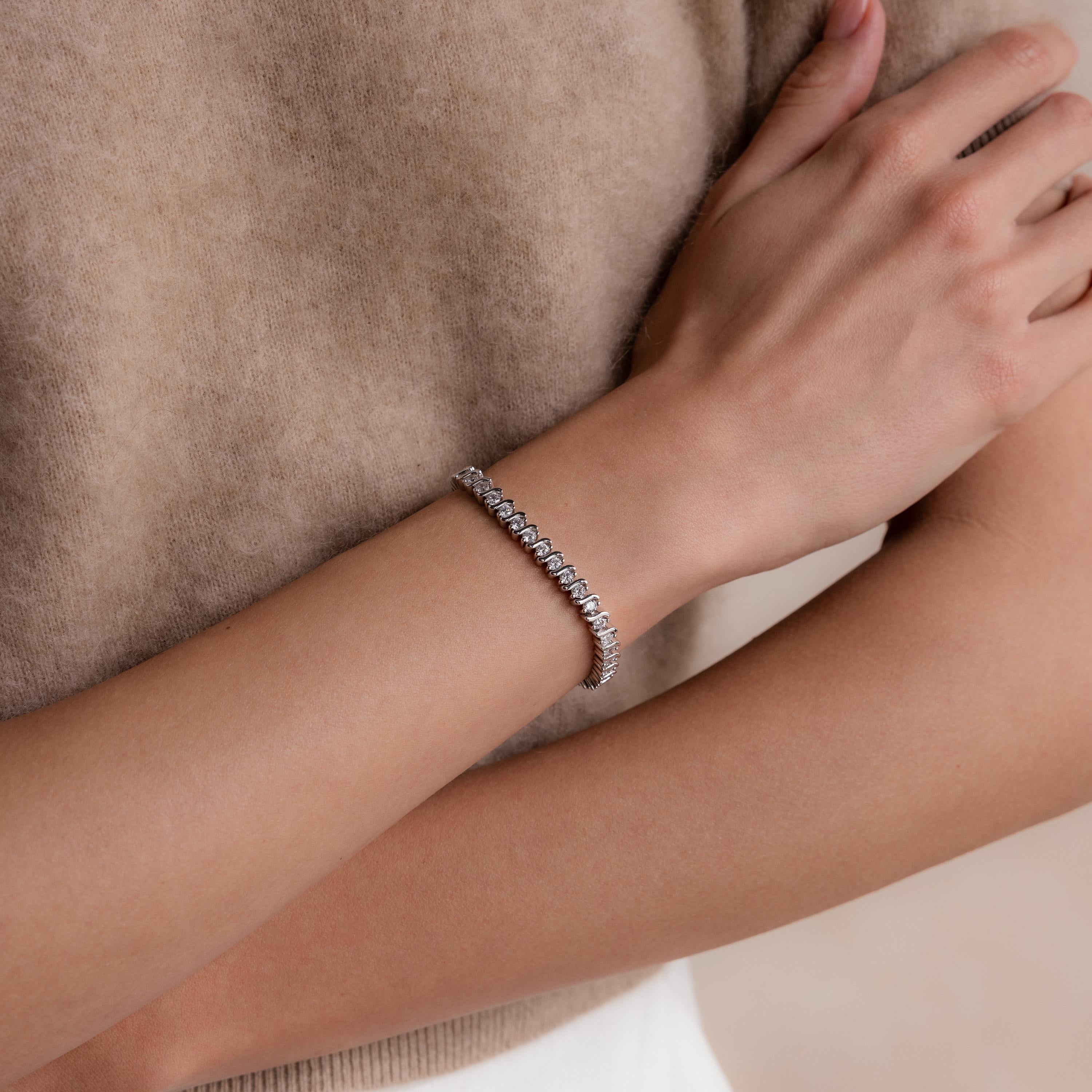 A person wearing the S-Link Diamond Tennis Bracelet, featuring shimmering stones on their wrist, styled with a beige top.
