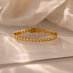 S-Link Diamond Tennis Bracelet featuring a twisted design with shimmering stones, displayed on a reflective white surface.