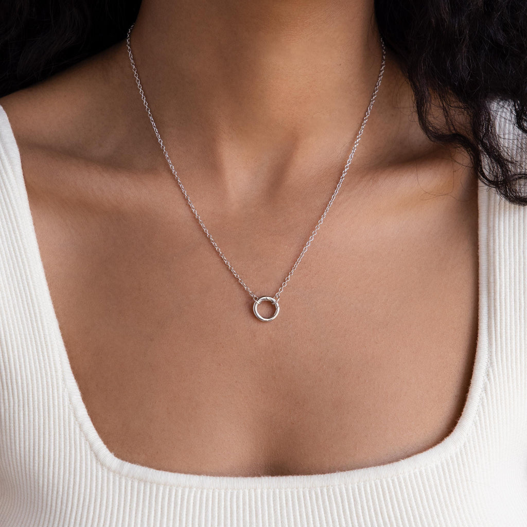 A woman wears the Cable Circle Charm Necklace featuring a small circular pendant over a white ribbed top.