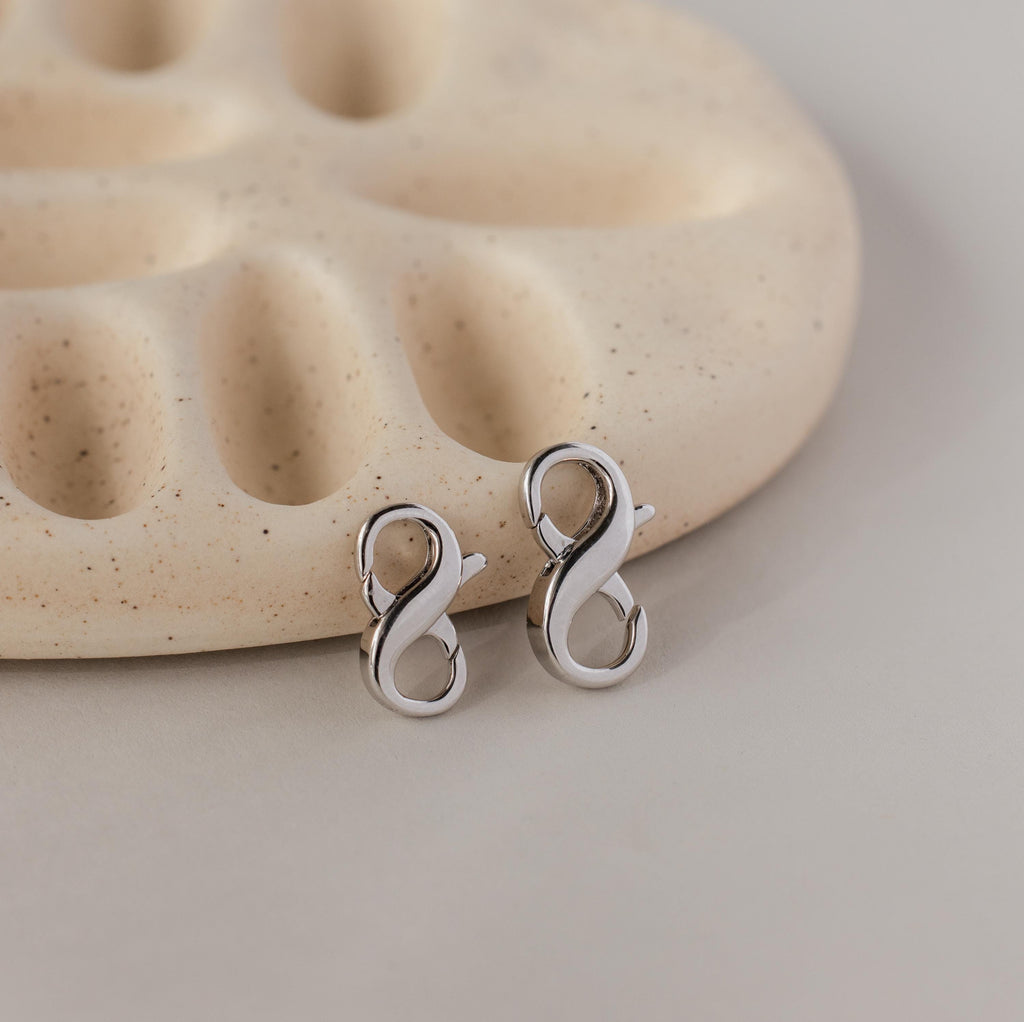 Multipurpose Lobster Clasp Extender Set in White Gold displayed on a beige, textured ceramic charm holder.