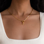 The Paperclip Clasp Necklace with collectible charms is styled on a woman's neck and paired with a white ribbed tank top.