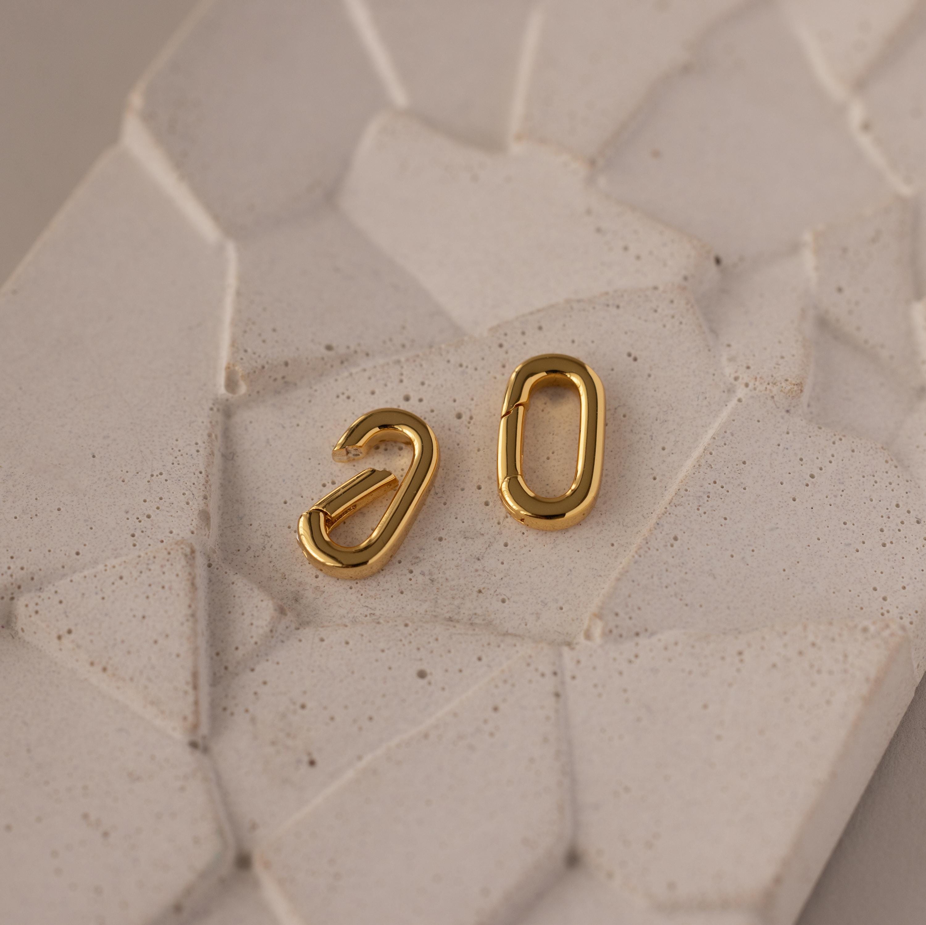 The Multipurpose Charm Hoop Clasp Set in White Gold features two oval charms on a light, textured surface—perfect for stacking bracelets or as a stylish charm connector.