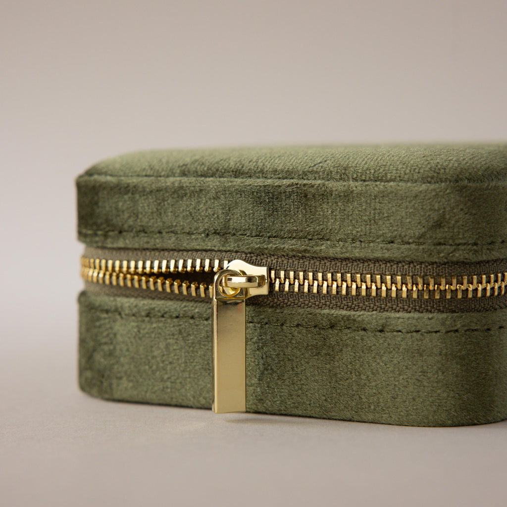 The Velvet Mirror Jewelry Box, in green velvet with a gold zipper, is shown close up against a neutral background—perfect as a stylish travel case for your favorite jewelry pieces.