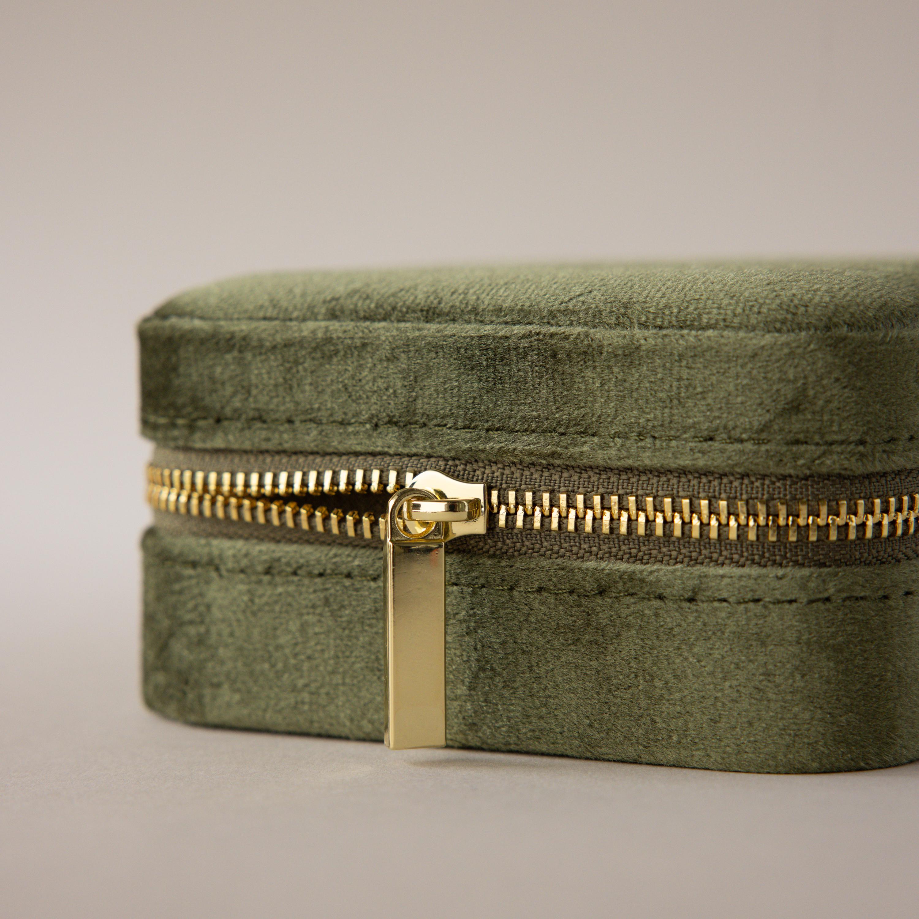 The Velvet Mirror Jewelry Box, in green velvet with a gold zipper, is shown close up against a neutral background—perfect as a stylish travel case for your favorite jewelry pieces.