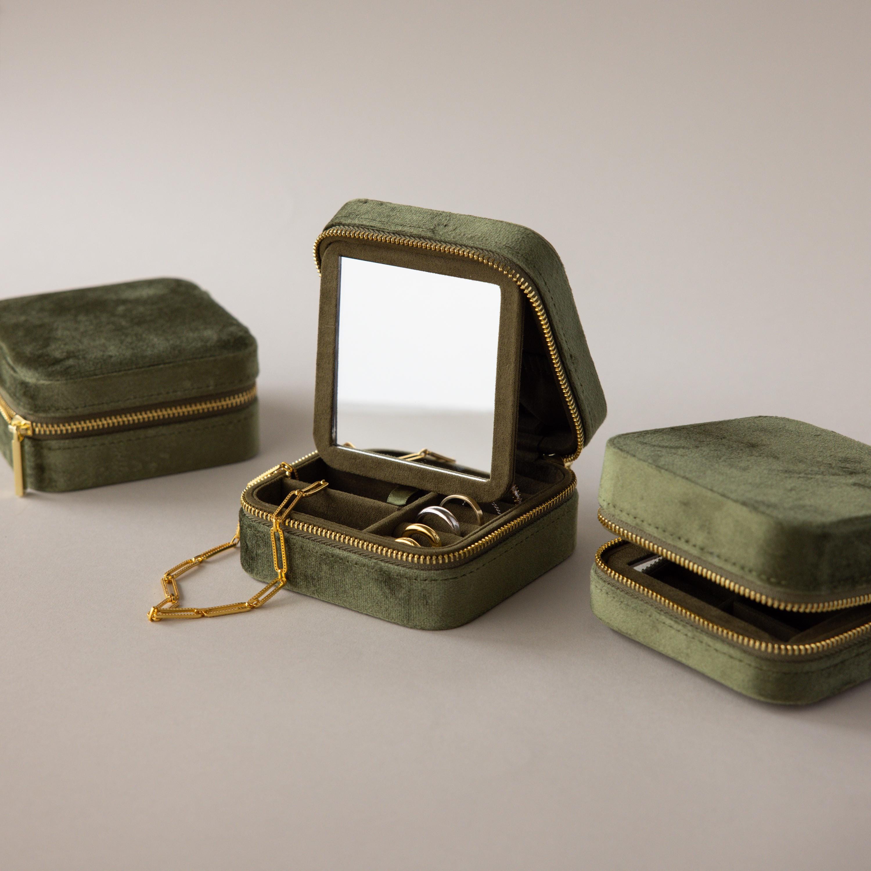 The Velvet Mirror Jewelry Box features green velvet, an interior mirror, and compartments displayed open with rings and a necklace inside.