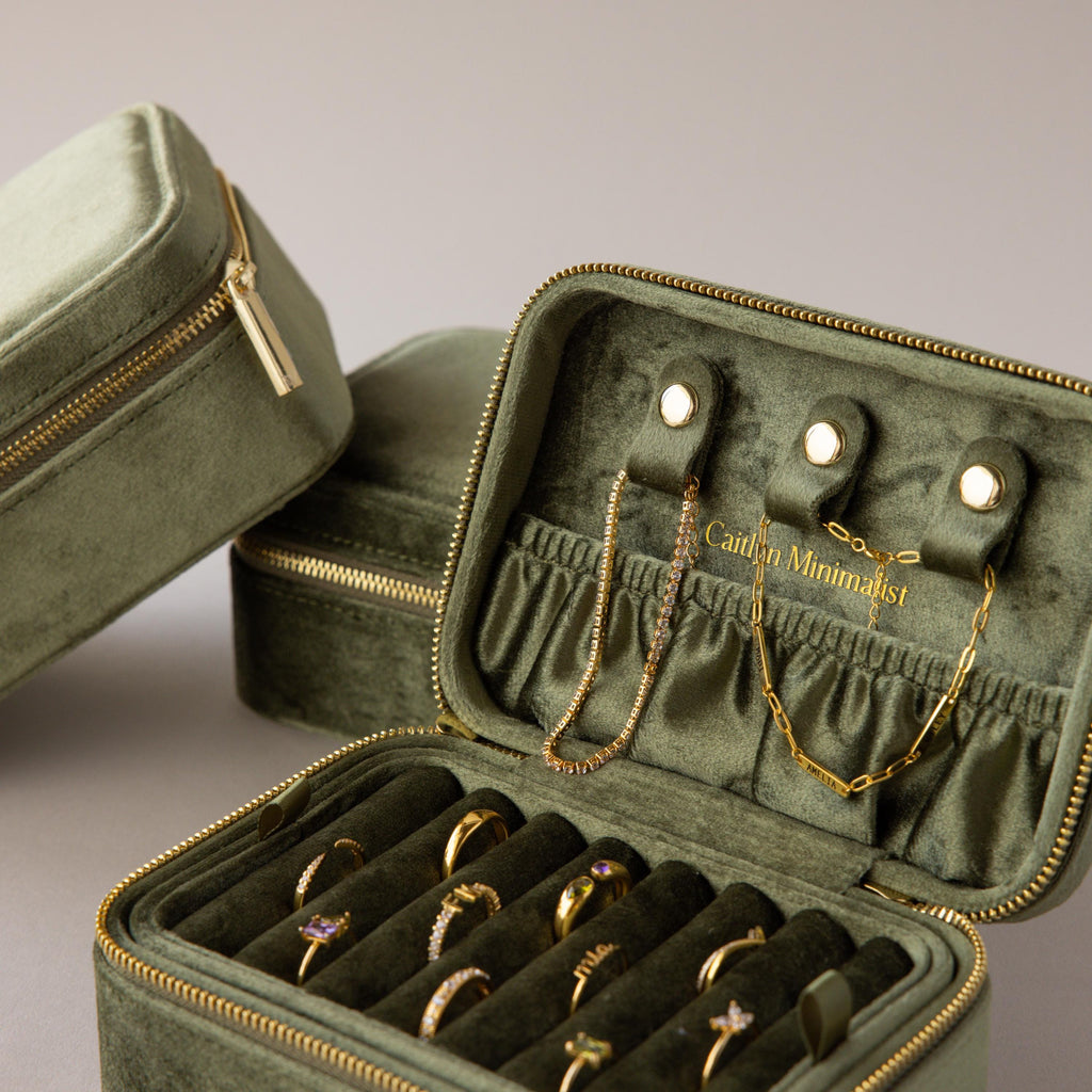 The Rectangle Velvet Jewelry Box, in green velvet, opens to neatly display and organize gold rings, necklaces, and bracelets.