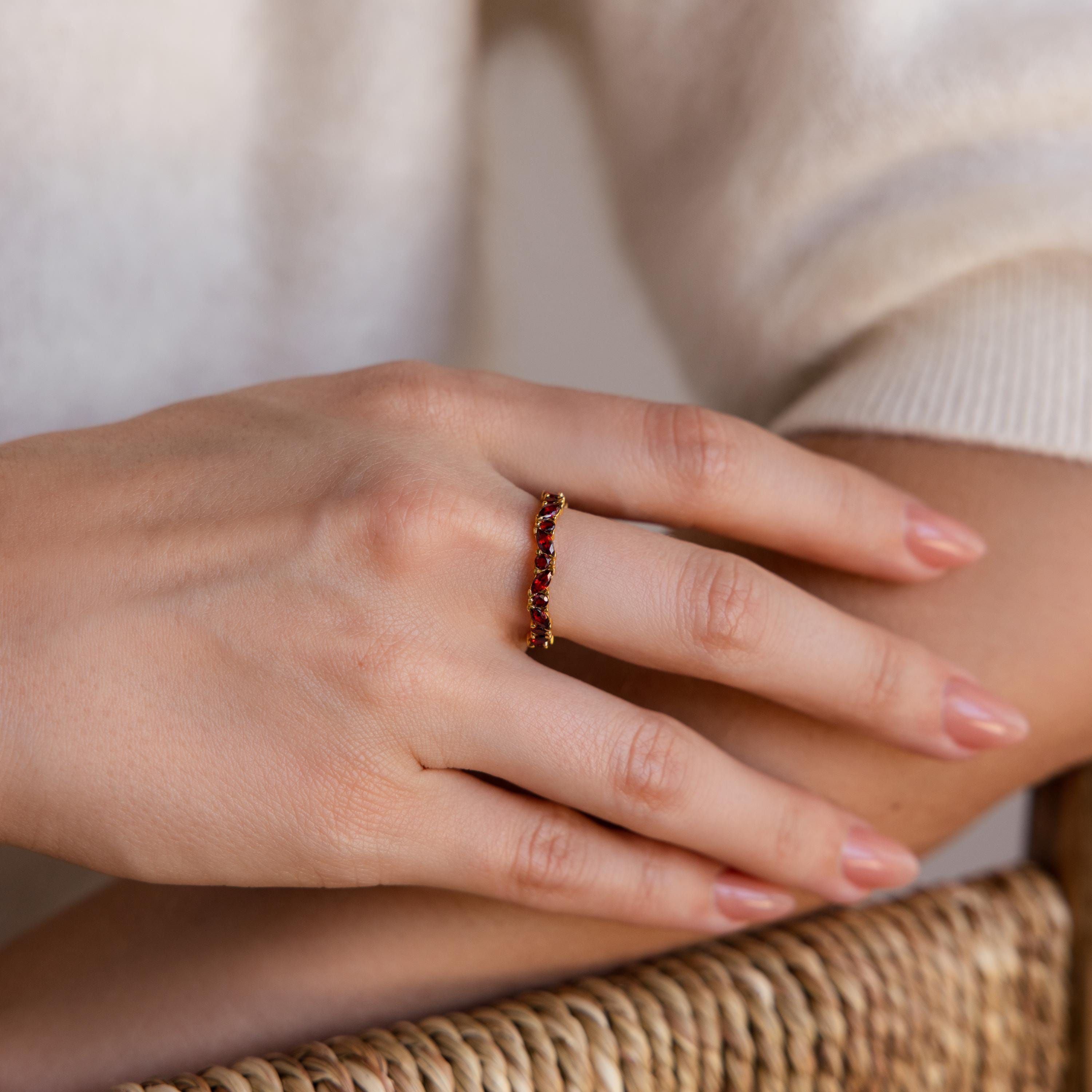 A hand wearing the Staggered Marquise Onyx Ring rests on a woven surface.