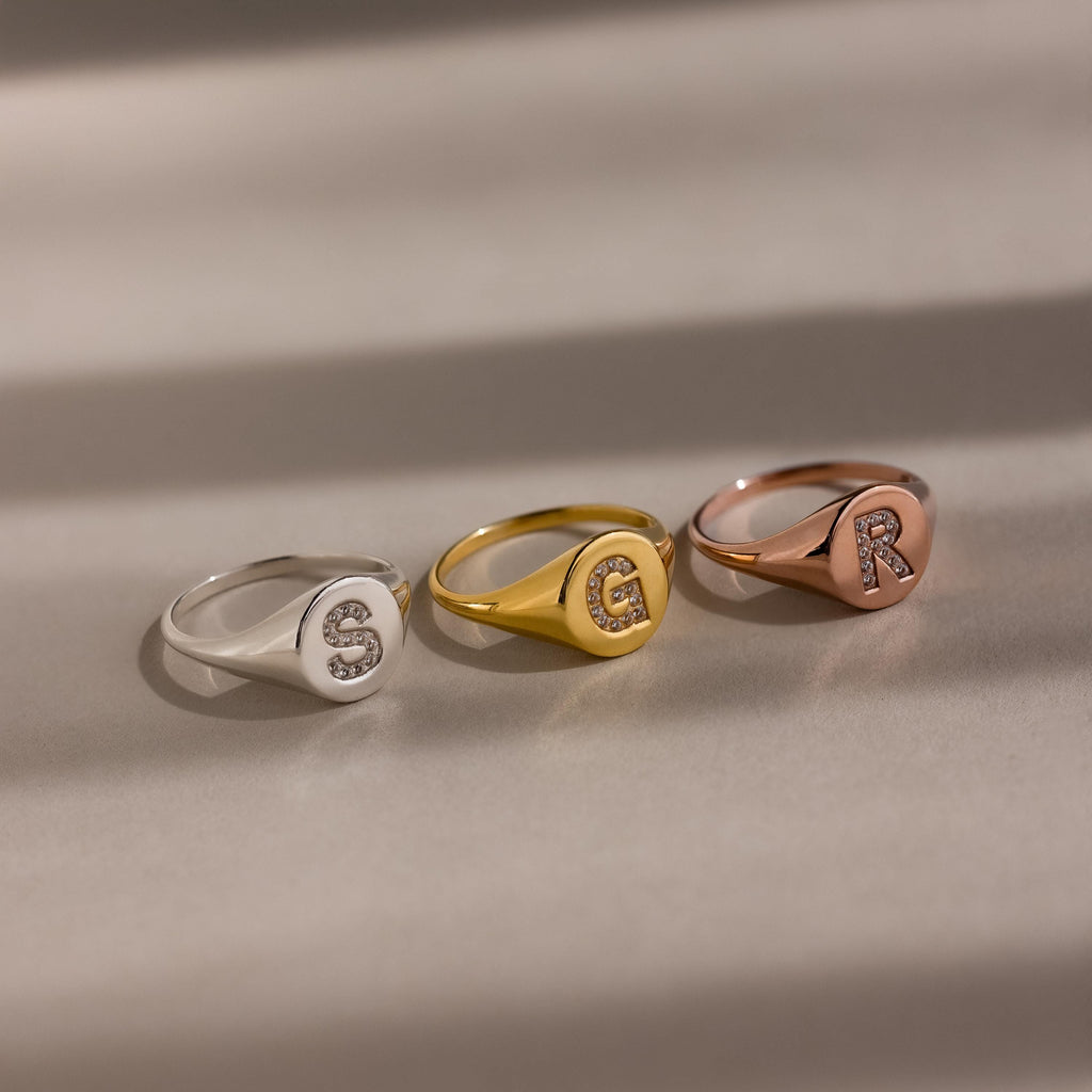 The Pave Initial Signet Ring comes in silver, gold, and rose gold with sparkling jeweled initials S, E, and R—ideal statement pieces for any occasion.