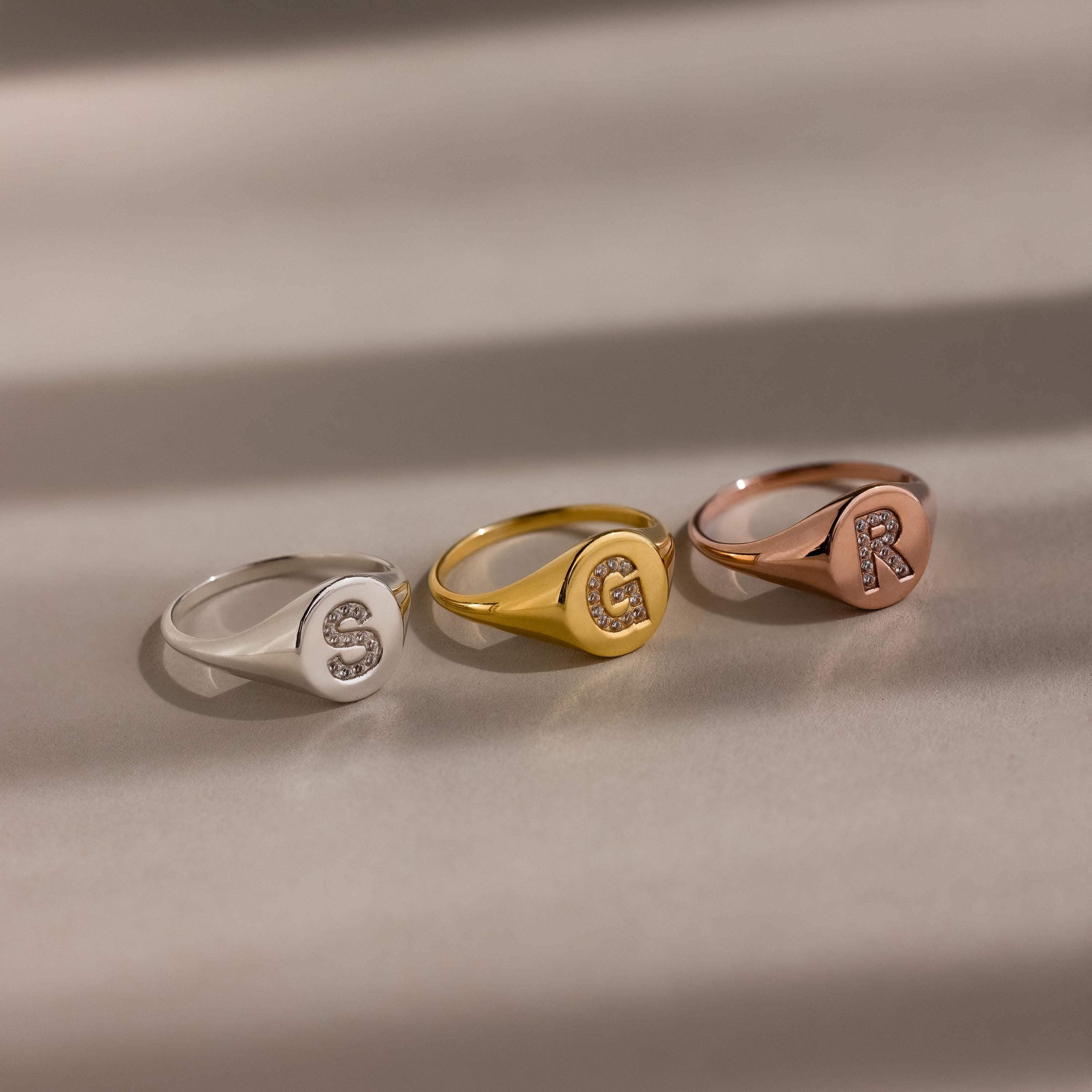 The Pave Initial Signet Ring comes in silver, gold, and rose gold with sparkling jeweled initials S, E, and R—ideal statement pieces for any occasion.