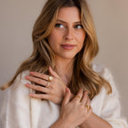 Woman with wavy blonde hair wearing a Pave Initial Signet Ring in Rose Gold and a white sweater, looking slightly to the side.