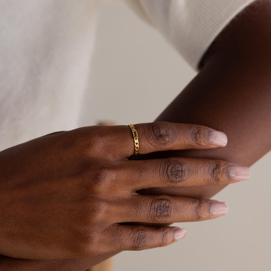 A close-up of a hand wearing the Baguette Pink Tourmaline Curb Ring against a neutral background, highlighting the ring's elegant personalized design and striking pink gemstone.