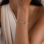 A woman wearing a Diamond Birthstone Tennis Bracelet and a cream-colored, sleeveless top.