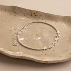 Diamond Tennis Letter Bracelet featuring the name ANDREA in sparkling letter charms, elegantly displayed on a speckled ceramic dish.