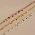 Diamond Tennis Letter Bracelets with names "LOUISE," "MAMA," and "CLARA" in rose, gold, and silver letters rest on a beige background—perfect minimalist personalized accessories.