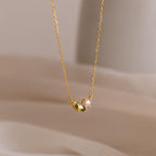 The Marquise Birthstone & Pearl Necklace features a gold chain, a leaf-shaped charm, and a small pearl—an elegant customizable birthstone necklace ideal for personalizing your look.