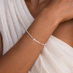 A woman wears the Venice Name Tennis Bracelet, featuring a nameplate charm spelling Jessica, paired with a white textured top.