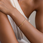 A person wearing the Venice Name Tennis Bracelet, featuring a delicate gold chain with a cursive "breathe" nameplate charm on their wrist.