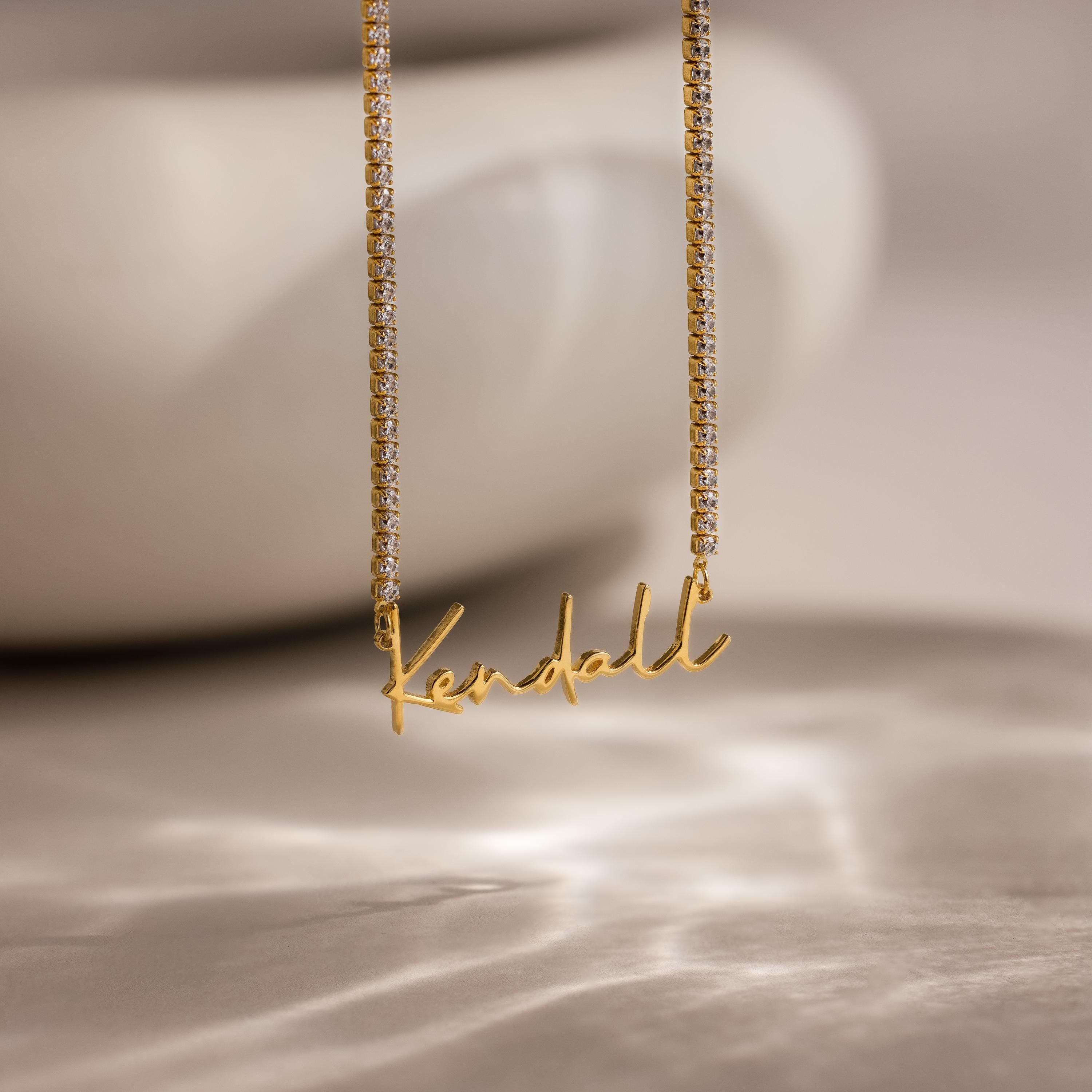Diamond Tennis Name Necklace with a Kendall pendant, featuring a sparkling diamond tennis chain, displayed on a soft, blurred background.