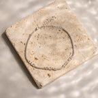 A silver Multiple Name Tennis Bracelet featuring letter charms spelling JULIE ABIGAIL ESTHER rests on a square marble tile.