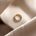 A Pave Aquamarine Charm Clip with sparkling blue gemstones rests on soft, beige satin fabric.