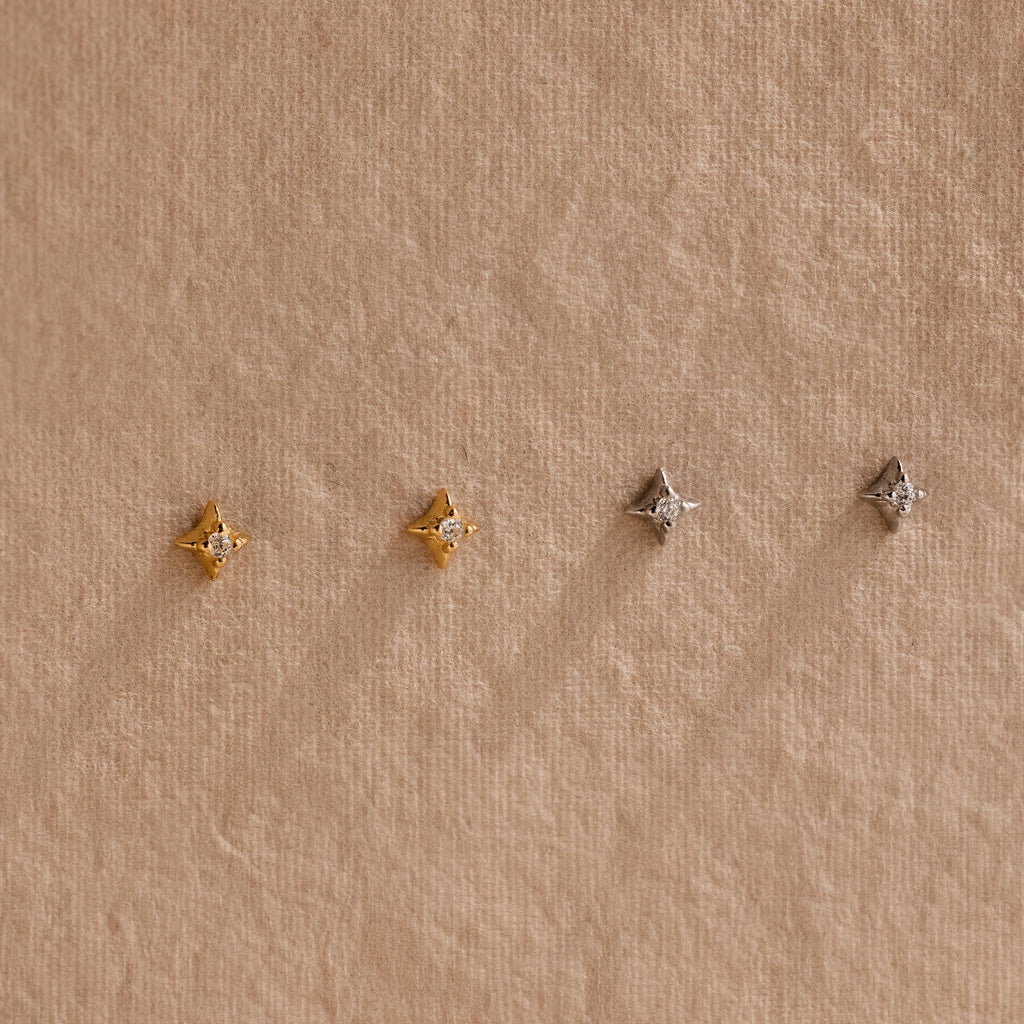 Two pairs of of gold and silver North Star Stud earrings hanging