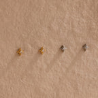 Two pairs of of gold and silver North Star Stud earrings hanging