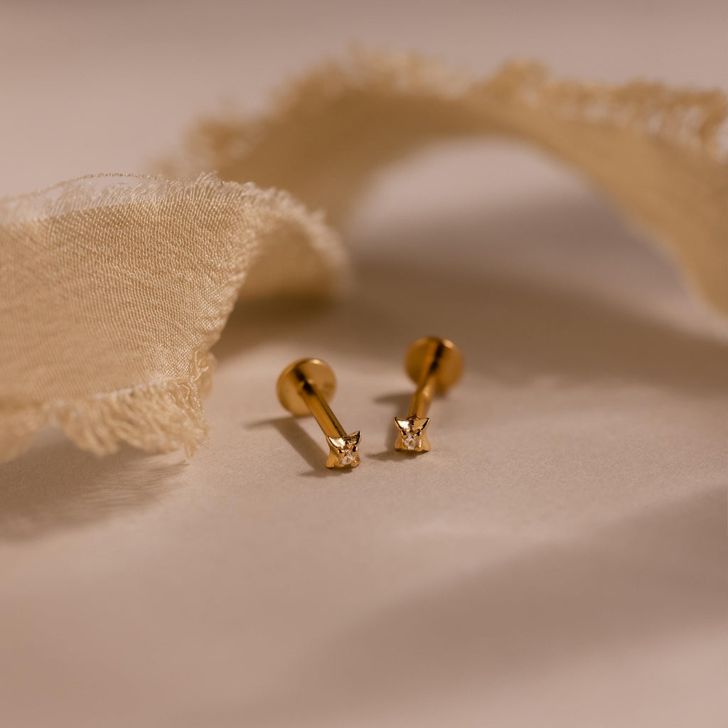 Close up of gold North Star Stud Earrings with flat backs. The earrings feature a north star design with a diamond earring in the middle