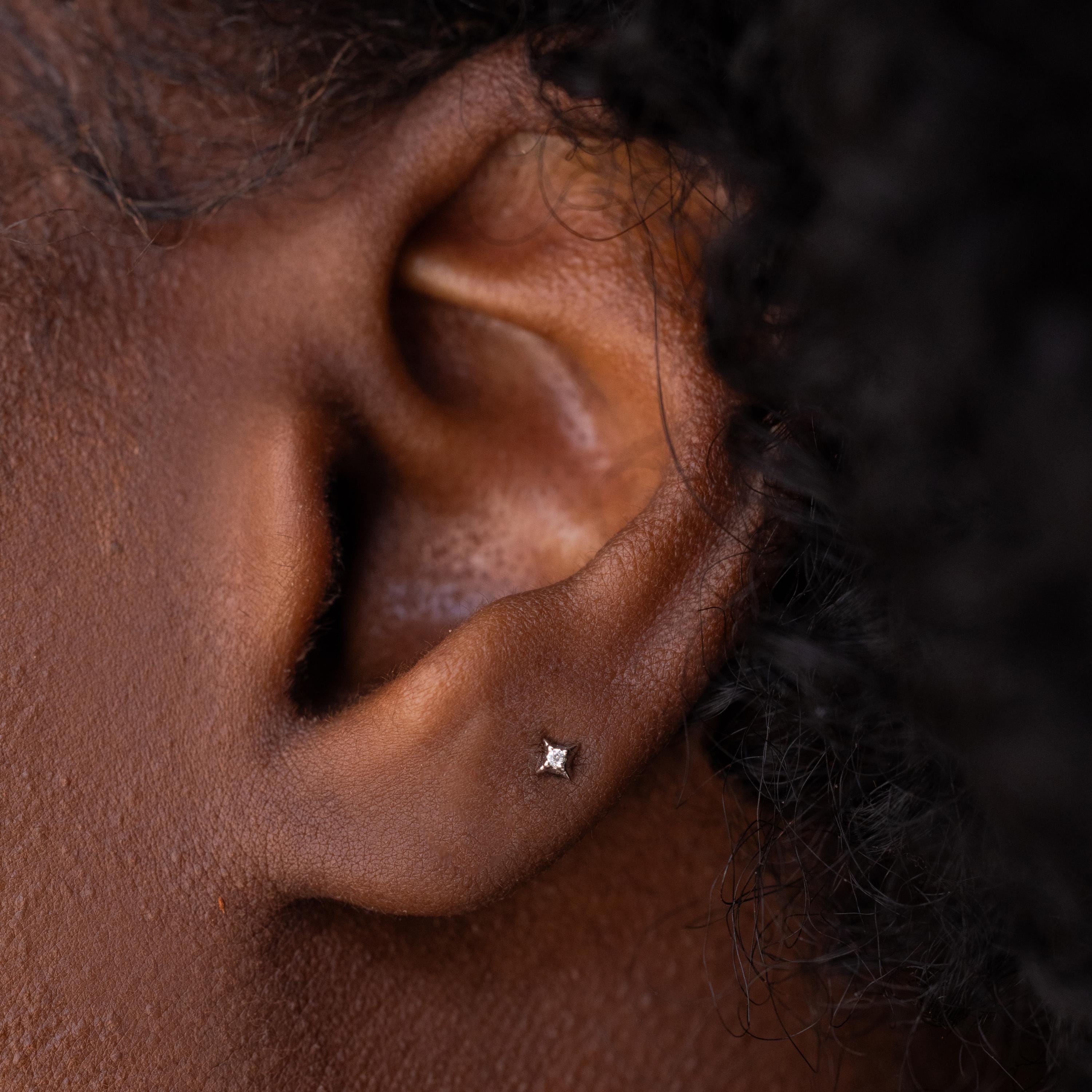 Dainty silver north star stud earring with tiny CZ diamond in center.