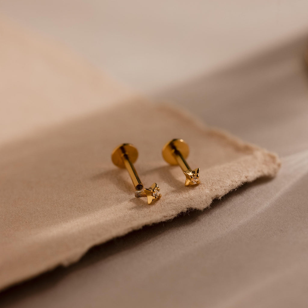 Close up of gold north star stud earrings with one screwed off, showcasing how the heart shaped flat back mechanism works