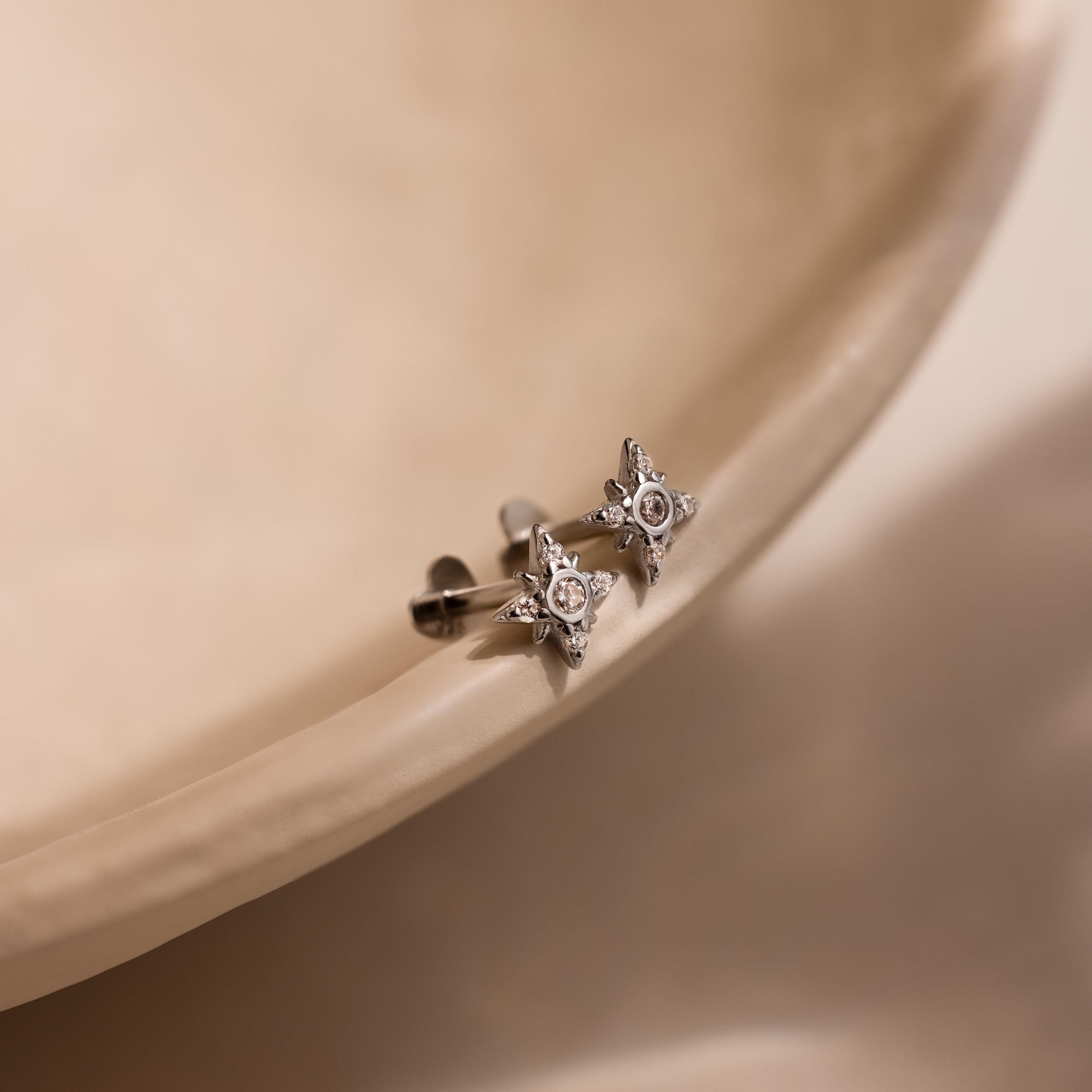 Flat lay of silver Pave North Star Earrings on soft beige surface