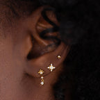 Close up of Pave North Star Earrings on a model's ear in the center, with a smaller star earring and a larger star drop earring aside them